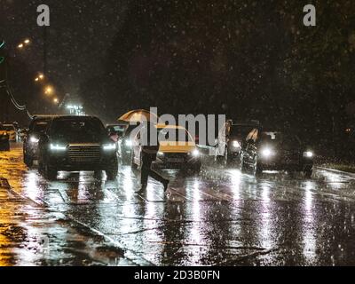 Moscou. Russie. 17 septembre 2020. Vue sur une traversée piétonne de la ville la nuit pendant une lourde averse. Silhouette d'un homme avec un parapluie Banque D'Images