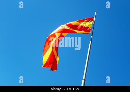 Drapeau de la macédoine du Nord agitant dans un ciel bleu ensoleillé Banque D'Images