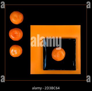 Composition de mandarine orange et de carré noir sur une table orange. Banque D'Images