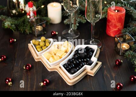 Assiette arbre de Noël avec olives vertes et noires, fromage.verres de champagne Banque D'Images