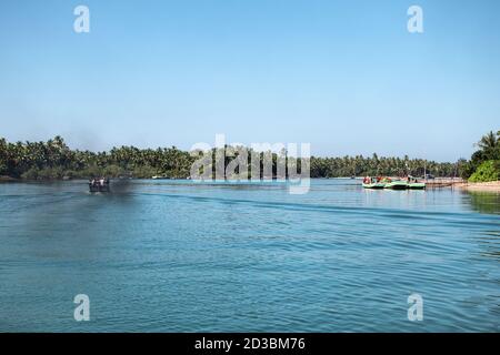 Quelques bateaux qui empruntent une rivière turquoise avec des mangroves vertes de chaque côté à Ngwesaung, au Myanmar Banque D'Images