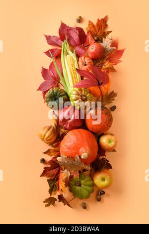 Composition verticale de la récolte d'automne, citrouilles, épis de maïs, feuilles d'automne colorées sur fond orange. Vue de dessus. Jour de Thanksgiving et Halloween. Banque D'Images