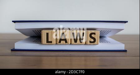 Les cubes d'un livre forment le mot « lois ». Le livre est couché sur une table en bois dans une bibliothèque. Belle table en bois, fond blanc. Concept d'entreprise, copie s Banque D'Images