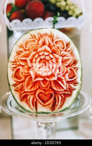 Art de la sculpture de pastèque sculptée belle fleur sur une grande pastèque à servir sur une table douce. Concept de la sculpture de fruits et de compositions végétales. Banque D'Images