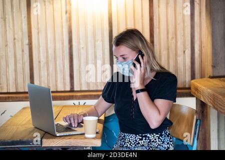 Femme portant un masque facial et un tablier rouge servant le client dans un magasin de wholefood sans gaspillage. Banque D'Images