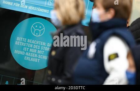 08 octobre 2020, Hessen, Francfort-sur-le-main : les passants portant une protection de la bouche et du nez marchent le long d'un panneau sur le Zeil de Francfort indiquant « Veuillez noter : l'entrée au magasin est autorisée uniquement avec une protection de la bouche et du nez ». Le nombre croissant de nouvelles infections de corona a également des conséquences de plus en plus importantes à Hesse. À partir du 9 octobre, des masques obligatoires seront introduits dans les galeries marchandes et les grandes rues commerçantes telles que le Zeil. L'alcool sera interdit dans les places, les rues et les espaces verts. Photo: Arne Dedert/dpa Banque D'Images