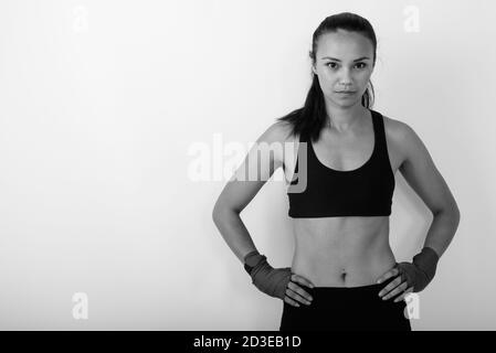 Photo en studio d'une jeune femme asiatique qui se pose avec les mains sur les hanches, sur fond blanc Banque D'Images