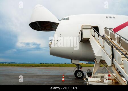 Un avion de transport Jumbo Jet avec un large nez ouvert porte de chargement en attente à une rampe de chargement pour un chargeur haut à décharger Banque D'Images