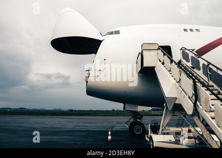 Un avion de transport Jumbo Jet avec un large nez ouvert porte de chargement en attente à une rampe de chargement pour un chargeur haut à décharger Banque D'Images