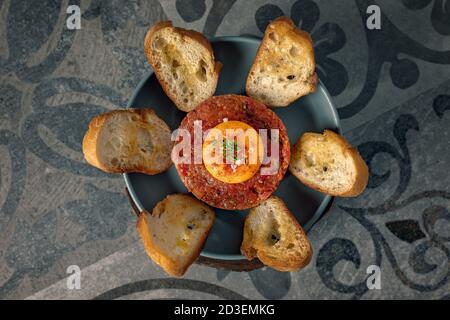 Tartre de bœuf fraîchement préparé avec du pain grillé et un œuf jaune Banque D'Images