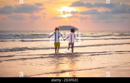 Enfant jouant sur la plage de l'océan. Les enfants sautent dans les vagues au coucher du soleil. Vacances en mer pour la famille avec les enfants. Petit garçon et fille courir sur l'île exotique duri