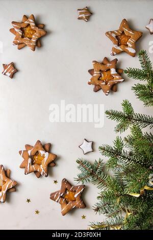 L'étoile de Noël Maison cookies caramel sucre forme avec le glaçage orange et de la confiture d'agrumes sur fond de marbre blanc avec des branches de sapin. Télévision lay, spac Banque D'Images