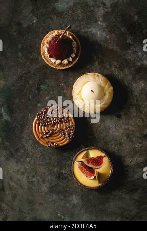 Variété de sweet tartelettes au chocolat, caramel, poires, figues plus vieux dark metal texture background. Mise à plat, de l'espace Banque D'Images