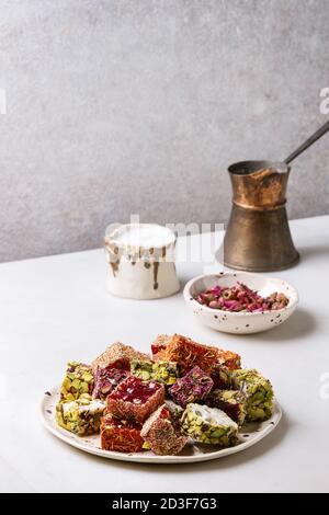 Variété de dessert traditionnel turc turcs goût différent et les couleurs des pétales de rose et de pistaches sur une plaque en céramique avec un jezve café Banque D'Images