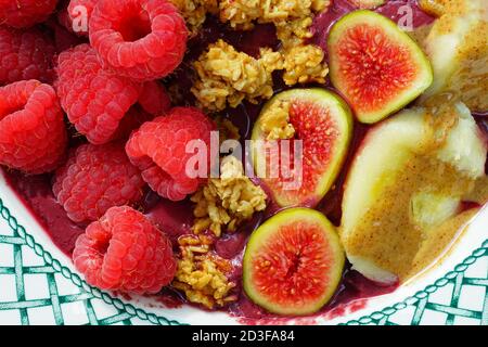 Vue sur un bol d'acai avec figues fraîches, framboises, banane et granola Banque D'Images