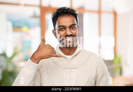 homme indien en chandail faisant un geste d'appel téléphonique Banque D'Images
