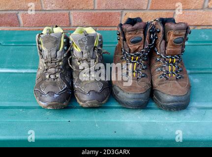 gros plan de 2 paires de chaussures de marche brunes à l'extérieur, séchage au soleil, bottes sales pour hommes et femmes sur boîte verte avec mur en brique en arrière-plan Banque D'Images