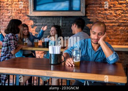 Un triste latin solitaire assis dans un bar ou un pub tout en buvant de la bière. Banque D'Images