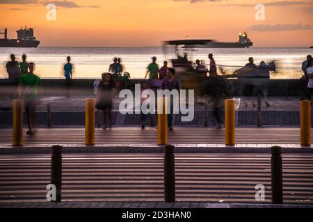 Coucher de soleil spectaculaire dans la baie de Manille avec piétons traversant et navires au premier plan. Banque D'Images