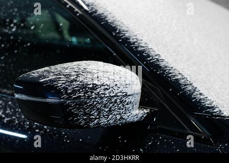 Des gouttes de mousse s'écoulant d'un rétroviseur latéral d'une voiture. Banque D'Images