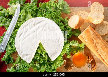 Camembert sur salade verte avec bol à miel et pain baguette Banque D'Images