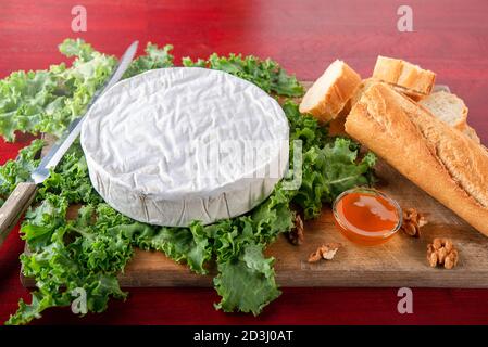 Camembert sur salade verte avec bol à miel et pain baguette Banque D'Images