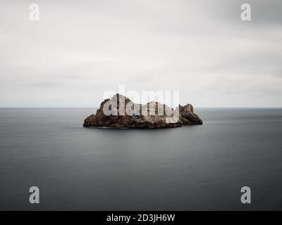 Paysage minimaliste d'une île dans l'océan. Los Urros, Liencres, Cantabrie, Espagne. Banque D'Images