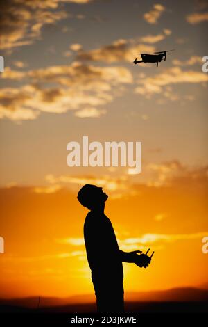 Silhouette d'un jeune homme utilisant un drone dans UN Cadre rural au coucher du soleil Banque D'Images