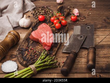 Tranche de boeuf cru sirlion steak sur planche en bois avec des tomates, l'ail et les asperges et la viande hache sur la table de cuisine et arrière-plan. Banque D'Images