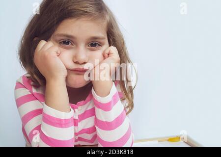 Portrait d'une triste fille frustrée fatiguée assise à la table, fille s'ennuyant. Difficultés d'apprentissage, concept d'éducation Banque D'Images