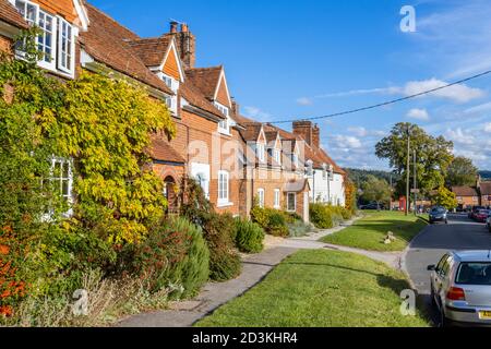 Vue sur les maisons et les chalets en terrasse typiques de briques rouges dans la grande rue principale de Great Bedwyn, un village dans l'est du Wiltshire, dans le sud de l'Angleterre Banque D'Images