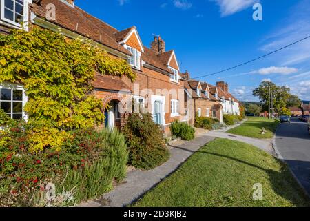 Vue sur les maisons et les chalets en terrasse typiques de briques rouges dans la grande rue principale de Great Bedwyn, un village dans l'est du Wiltshire, dans le sud de l'Angleterre Banque D'Images