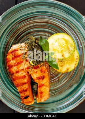 Steak de saumon grillé avec courgettes en tranches et basilic sur l'assiette. Banque D'Images