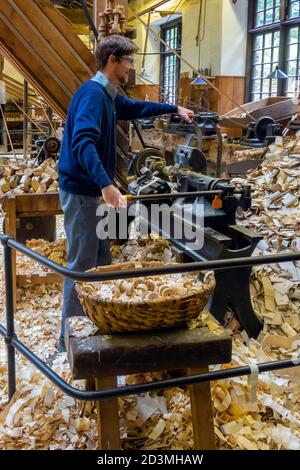 Un homme faisant la démonstration d'un tour de tournage de bois dans le Stott Park Bobbin Mill pour la fabrication de bobines en bois pour le industrie textile Banque D'Images