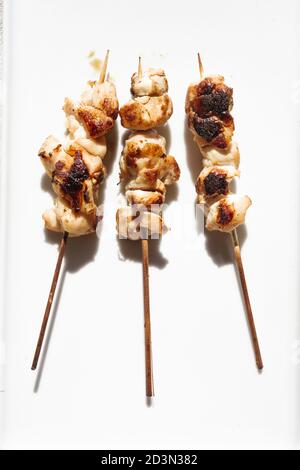 Petites pièces brochette de poulet sur un plat blanc sur une table en bois rustique bleu, thème barbecue, lumière dure avec ombre edgy définie Banque D'Images