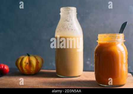 Soupe de punaise et de tomate sur un pot en verre sur un couteau en bois sur fond rouillé, avec une bouteille de soupe de pommes de terre à l'arrière, Banque D'Images