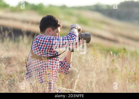 photographe jeune homme parlant des images dans la nature au coucher du soleil Banque D'Images