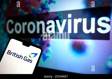 Le logo British Gas affiché sur un téléphone portable avec un modèle d'illustration du coronavirus affiché sur un moniteur en arrière-plan. Banque D'Images