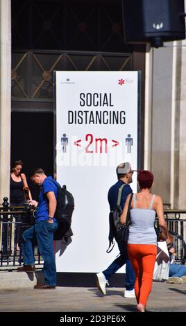 Les personnes qui marchent devant un panneau social de rue distanciant sur Oxford Street, Londres, 2020. Banque D'Images