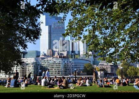 Vue de jour sur les personnes assises dans le parc Potters Fields avec Ville de Londres en arrière-plan Banque D'Images