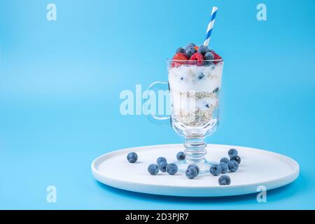 Dessert avec baies et crème et céréales sur fond bleu. Banque D'Images