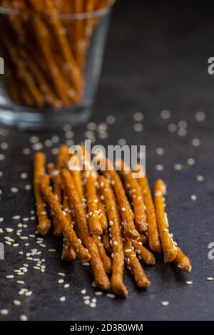 Bâtonnets salés. Bretzels croquants aux graines de sésame sur table noire. Banque D'Images