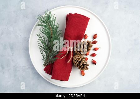 Table de Noël, assiette blanche décorée de serviettes et de branches en pin et de branches en sapin. Banque D'Images