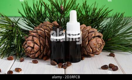 Cône de pin avec noix et bouteille de verre sur une table en bois blanc Superfood biologique et sain. Banque D'Images