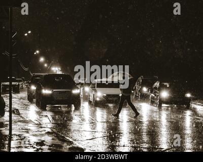 Moscou. Russie. 17 septembre 2020 passage piéton dans la ville la nuit pendant une grosse averse. Silhouette d'un homme avec un parapluie dans la lumière Banque D'Images