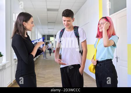 Groupe d'étudiants adolescents parlant à une enseignante dans couloir scolaire Banque D'Images