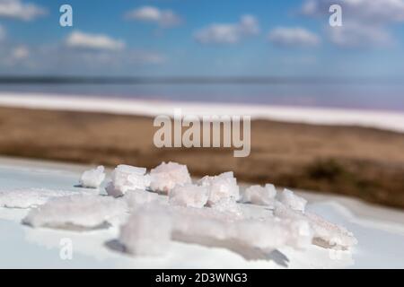 Flocon de sel blanc rose cristaux de bande sur la surface blanche réfléchissante avec le fond rose flou lac salé paysage. Station thermale ensoleillée en gros plan Banque D'Images