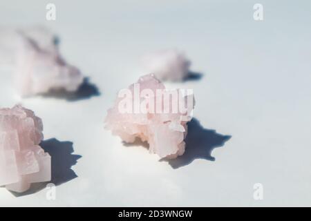 Bande de cristaux de flocons de sel blanc rose sur une surface brillante réfléchissante blanche. Centre thermal avec ingrédients cristallisés, gros plan lumineux et sélectif Banque D'Images