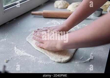 Préparation de la pâte pour la cuisson, la congélation, la sculpture et d'autres blancs de nourriture - un grand morceau de la pâte est sur la table le chef découpe petit Banque D'Images