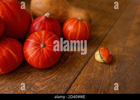 Une couche plate de petits citrouilles hokkaido rouges se trouve sur le plancher en bois. Décorations d'Halloween. Copier l'espace. Carte postale pour les vacances. Légumes frais d'automne Banque D'Images